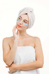 Young woman posing on a white studio background in a bath towel. Spa, body care and spa treatments concept.