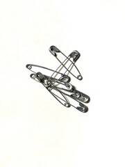 Fototapeta premium Silver metal safety pins isolated on white background. Used for fashion, hobby, crafts, or household.