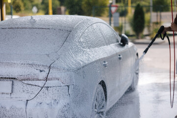 Cleaning car using active foam. Handsome man washing his luxury car on self car-washing