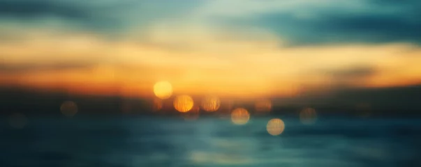 Abstract blurry natural background of sunset skyline and water surface, warm golden hour mood