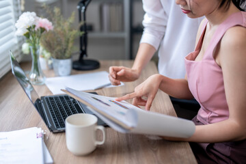 A woman is sitting at a desk with a laptop and a cup of coffee