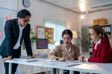 Three women and a man are sitting at a table in a conference room