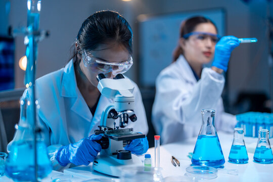 Asian scientist using microscope analyzing sample in laboratory