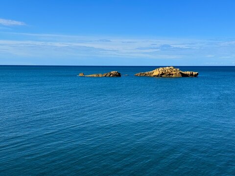 Blue sea, sky and rocks in water on horizon