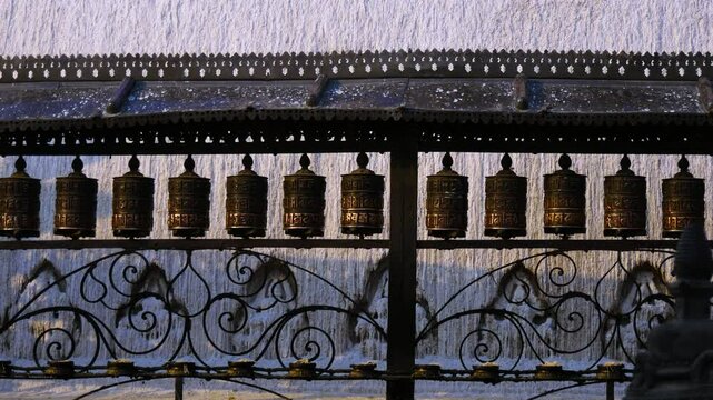 One spinning Buddhist prayer wheel among long line of prayer wheels from the Buddhist temple Swayambhunath stupa a UNESCO world heritage site.