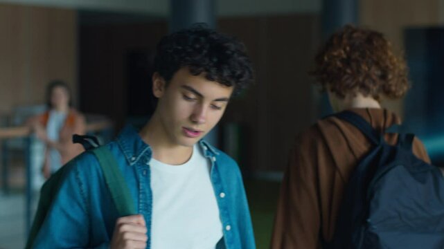 Caucasian male man guy pupil student schoolboy teenager walking going in corridor hallway in university college school sad upset bullying classmate boy pushing shoulder push bully violence problem