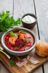 National dish of Ukrainian cuisine borscht with vegetables, turkey meat, herbs, sour cream and traditional bread (bun with garlic and dill, pampushka) with bacon (pork). Cultural heritage.