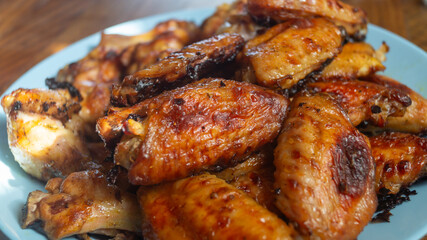 Chicken wings baked in the oven on a plate on a wooden table close-up
