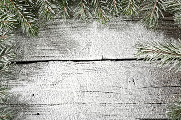 Pine green branch on festive winter snowy background. Wooden board with empty space for products. Winter ornaments and winter signs and decorations and figurines from a template