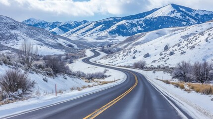A remote highway winding through snow-covered mountains, completely empty and serene