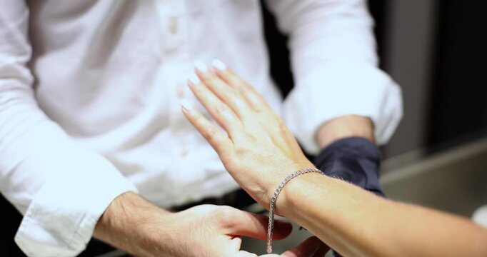 A woman in a jewelry store measures a bracelet, close-up. The concept of choosing a diamond jewelry
