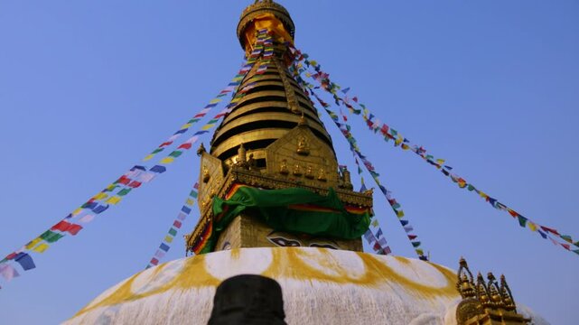 Panning from Buddha statue to UNESCO world heritage site Swayambhunath Stupa a Buddhist temple with colorful Tibetan prayer flags in Kathmandu Valley.