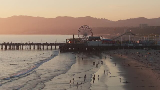 Aerial view of the Santa Monica Pier in California, Los Angeles at sunset. Beautiful summer landscape at the Santa Monica Pier with a Ferris Wheel, rollercoaster, carnival rides and games