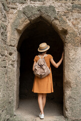 A female traveler takes in the sights in the old town while walking through the ancient fortress and standing in an arch among the stone walls