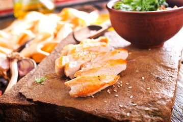 Grilled chicken breast with spice rub and lemon on a cutting board, sliced and whole