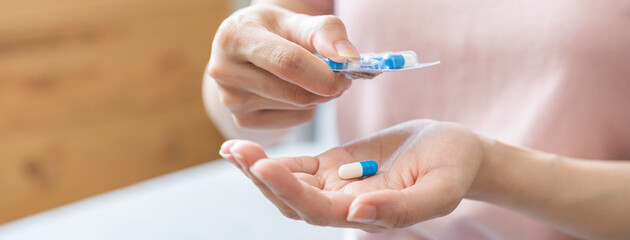 Sick ill asian young woman, girl hand taking tablet pill capsule out from blister pack, painkiller medicine from stomach pain, head ache, pain for treatment, take drug or vitamin at home, health care.