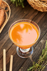 A glass of fresh carrot juice on a wooden table with ecological bamboo straws. Zero waste.