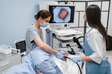 Doctor using a fiberoptic scope at gastroscopy in modern operating room. Gastroenterologist using...