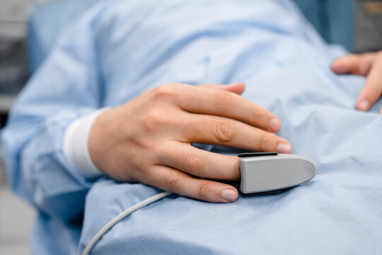 Selective focus on the pulse oximeter on the patient's finger. Determination of oxygen saturation of the human body during surgery in a hospital. Pulse oximetry.