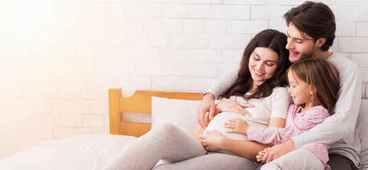 Happy family of three expecting second baby. Happy man embracing his pregnant wife and little...