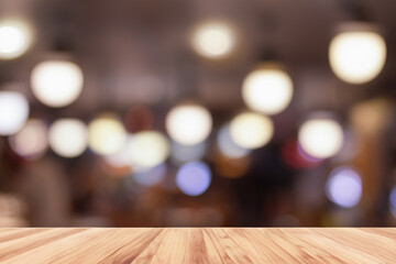 Wooden tabletop with blurry background of bokeh lights and people.