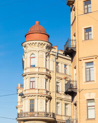 Fototapeta premium Close-up of a historic residential building with a tower and ornate facade in sunlight. Architectural details of a European city.
