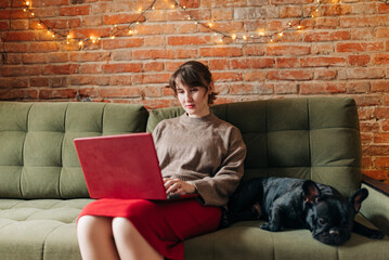 Young woman student or businesswoman studying at home using digital table with her pet French bulldog lovely cute dog in apartment indoors lifestyle