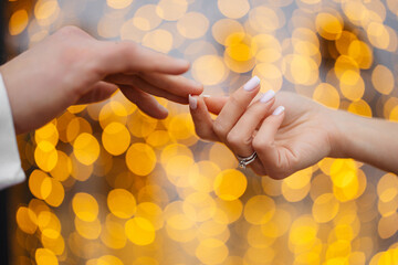 hands of a married couple on a bokeh background
