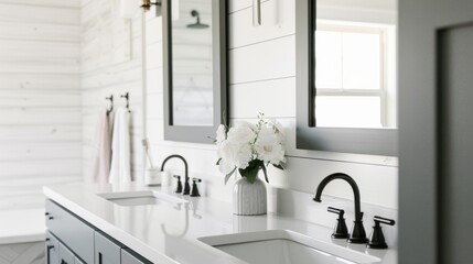 Elegant and pristine white bathroom with twin sinks, black fixtures, and a vase of white flowers, offering a clean and modern aesthetic.