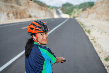 cheerful female cyclist smiling when riding bike, rear view