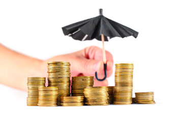 Hand Holding Black Toy Umbrella Over Stacked Coins for Protection