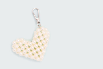 Keychain in a heart shape made from pearl imitation beads on a blue background.