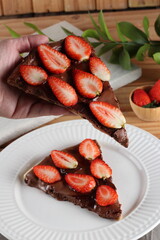 Prato com fatia de pizza de chocolate e morangos fatiados