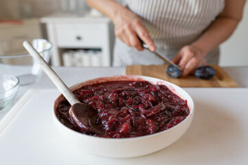 Fresh and homemade cooked plum chutney prepared by a woman with apron in the kitchen