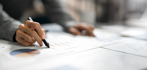 Closeup hand of Business men analyze company results and profits with graph statistics.