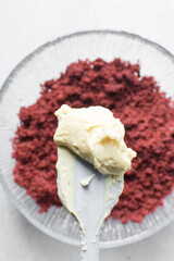 Overhead view of vanilla buttercream on crumbled red velvet cake, buttercream frosting on cake crumbs, process of making red velvet cake pops