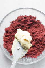 Overhead view of vanilla buttercream on crumbled red velvet cake, buttercream frosting on cake crumbs, process of making red velvet cake pops