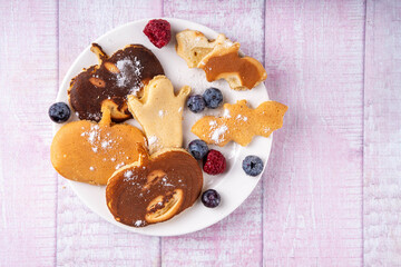 Halloween kids food treat. Funny pancakes in form of cute bat with witch hat. Breakfast snack for child's Halloween party, with berries & candy