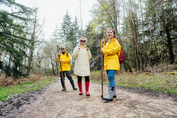 Fototapeta premium Group of friends walking with backpacks in forest. Trekking travel in adventure lifestyle, nature hiking in vacation holiday with journey. Tourism, hiking, and friendship concept. Outdoor activities