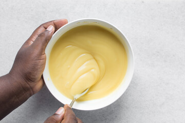 Overhead view of nigerian akamu being made in a white bowl, pap akamu or ogi in a white bowl, top...