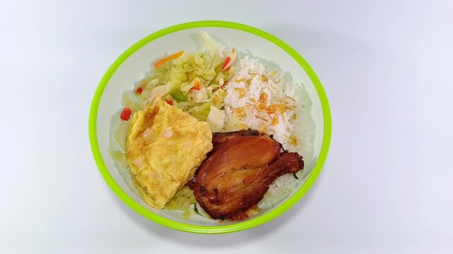 Grilled chicken thigh, plain omelette, and stir-fried cabbage mixed with sliced carrots and chillies, served with steamed rice on a plate with a green accent, against a clean white background