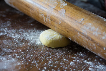 Photograph of hands flattening some dough with a rolling pin.