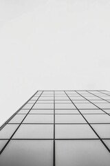 View from below a modern glass building, showing geometric patterns with a clear sky as the backdrop, emphasizing structure.