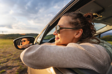 Happy young woman drivier looking out of car window, auto travel and adventure