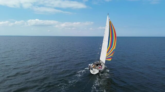 Aerial drone 4K film of sailboat yacht with colorful spinaker sail sailing on sea ocean water with Dutch holland flag