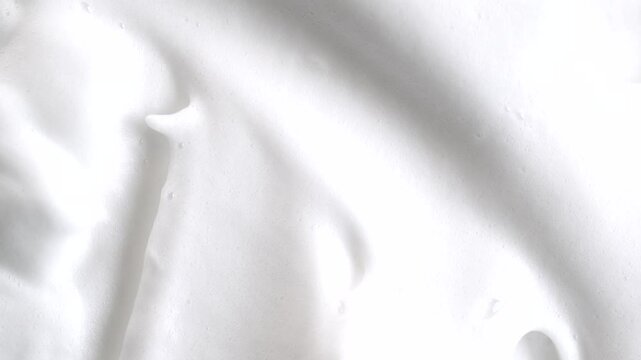 Beauty background with foam mousse, macro. Close up of white cloud of shaving mousse foam, rotation. Soap suds