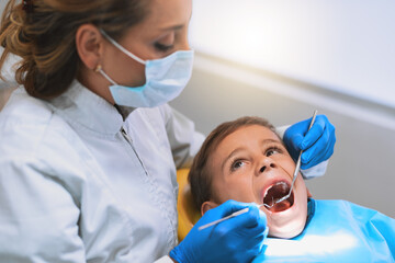 Child, dentist and consultation for checkup in hospital for procedure or examination in oral care clinic. Woman, patient and mask with tools as orthodontist for teeth cleaning or root canal treatment