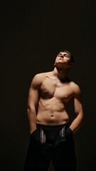 Portrait of handsome young man with muscular, relief body, torso, posing shirtless against dark studio background. Concept of male beauty, body and skin care, health, sport