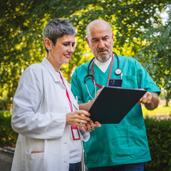 Two doctors man and woman review patient data with mobile phone