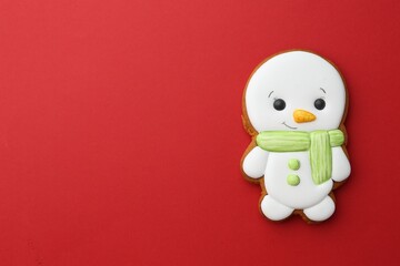 Tasty Christmas cookie in shape of snowman on red background, top view. Space for text